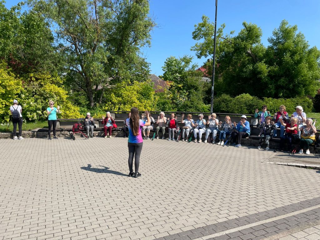 Bauskas pastaigas dalībnieki atpūtas pauzē vingro fizioterapeites Vinetas Briedes vadībā.